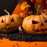 Two carved pumpkins with spooky faces set against an autumnal background for Halloween.